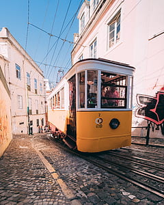 yellow and white train between houses thumbnail