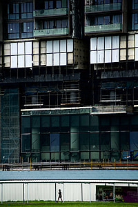 person walking on grassfield near green building thumbnail