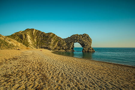 brown sand beach with rock formation on seashore thumbnail