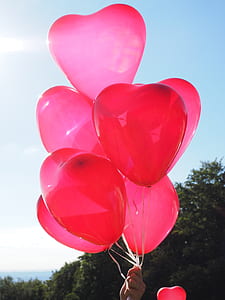 person holding heart-shaped pink balloons thumbnail