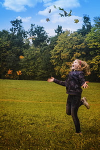 Girl in Black Jacket Standing on Green Grass during Daytime thumbnail