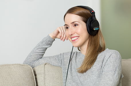 woman wearing black corded headphones while sitting on sofa thumbnail