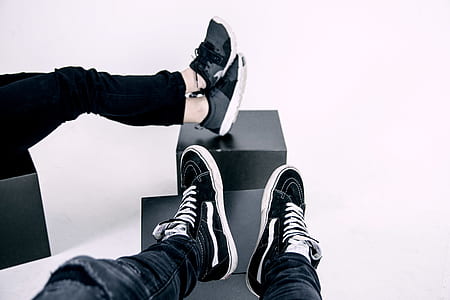 two pairs of black sneakers on top of ottomans thumbnail