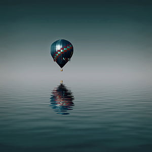 hot air balloon flying over body of water thumbnail