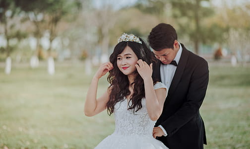 Groom Tying Bride's White Lace Wedding Gown at the Back thumbnail