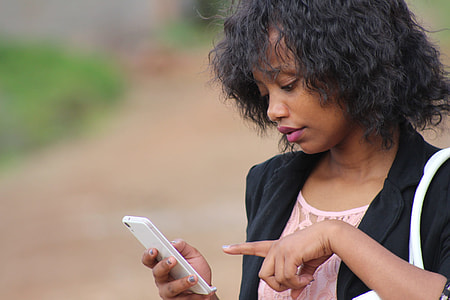 black haired woman in black formal coat holding a white smartphone thumbnail