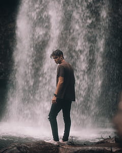 photo of man standing in front of waterfall thumbnail