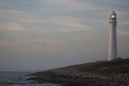 white lighthouse near  body of water during nighttime thumbnail