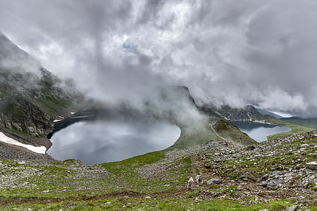 Green Grass Covered Ground Near Body of Water Under Gray Cloudy Sky thumbnail