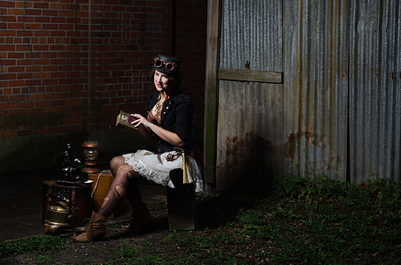 woman in black steampunk costume sitting near brown concrete brick wall thumbnail