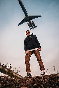 low angle photography of man standing under flying airline thumbnail