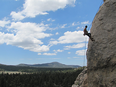 man rock climbing under white clouds and blue sky during daytime thumbnail
