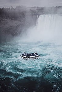 white boat on body of water near waterfalls at daytime thumbnail