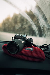 minolta DSLR camera on The North Face beanie cap inside vehicle during daytime thumbnail