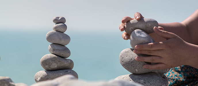 person doing gravity glue on stones during daytime thumbnail