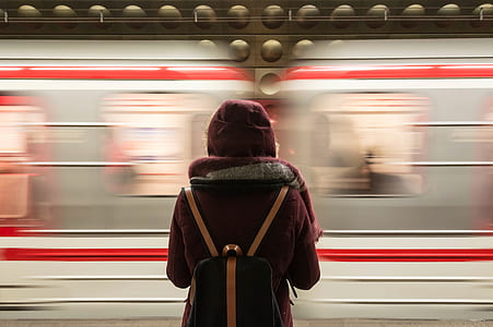 person wearing red hoodie carrying black leather backpack standing near train thumbnail