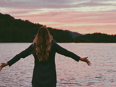 woman wearing black long-sleeved dress in front of body of water thumbnail