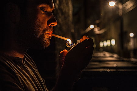man lighting cigarette during night time thumbnail