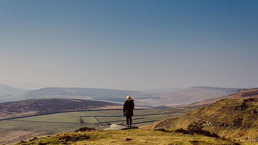 woman standing on edge of mountain with a view of green field thumbnail