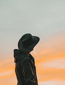 man wearing black jacket and hat facing sun thumbnail
