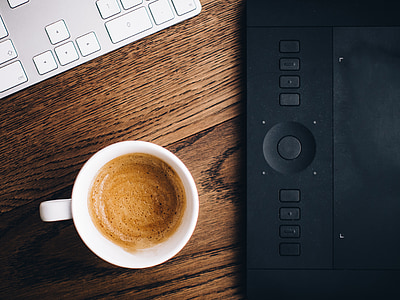 flat lay photography of white ceramic mug filled with coffee beside black graphics tablet thumbnail