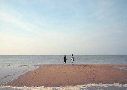 two children playing on seashore under clear blue sky thumbnail