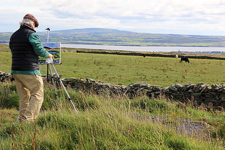 man standing on green field while painting thumbnail