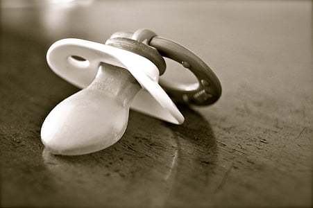 closeup photo of greyscale pacifier on brown wooden table thumbnail