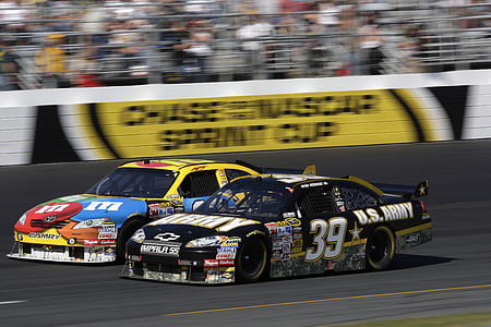 two black and yellow stock cars on gray road in full speed thumbnail