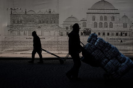 silhouette of two person pushing and pulling hand trucks thumbnail