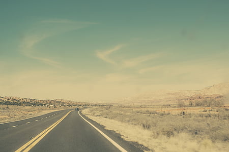asphalt road with double yellow lane between brown grasses during daytime thumbnail
