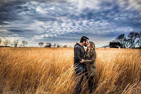 man and woman kissing under white clouds and blue sky during daytime thumbnail