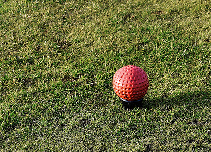 red golf ball on grass field thumbnail
