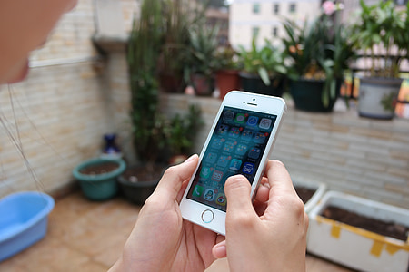 person holding gold iPhone 5s displaying home screen thumbnail