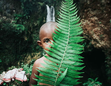 boy standing behind green leaf thumbnail