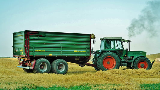 green tractor and utility trailer surrounded by green grass thumbnail
