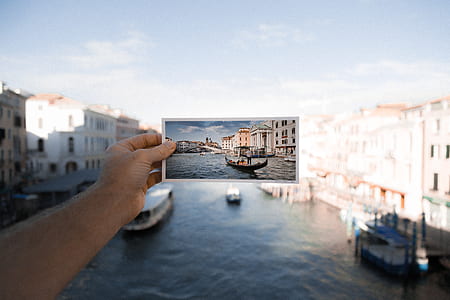 person holding photo of black boat on body of water during daytime thumbnail