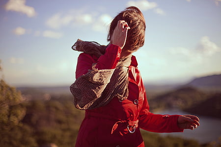 woman wearing red leather coat with brown scarf scratching her head selective focus photography thumbnail