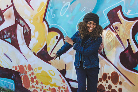 woman wearing blue denim jacket and blue jeans near graffiti wall thumbnail