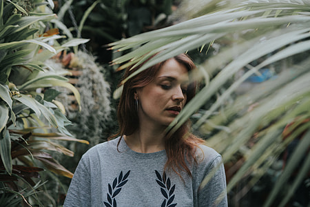 woman in gray and black floral crew-neck top surrounded by plants thumbnail