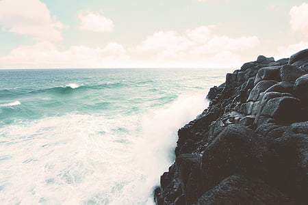 waves crashing on rock formation during daytime thumbnail