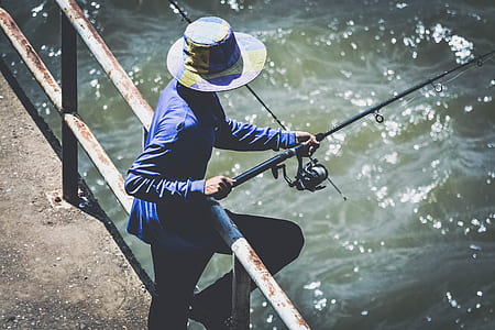Person in Blue Long Sleeve Shirt and Black Pants Using Fishing Rod thumbnail
