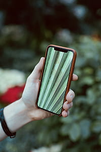 person holding space gray iPhone X and brown case thumbnail