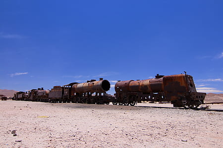 brown train on railways under clear blue sky thumbnail