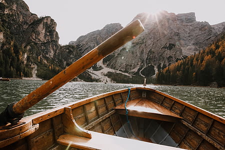 Brown Wooden Canoe on Body of Water Near Mountain thumbnail