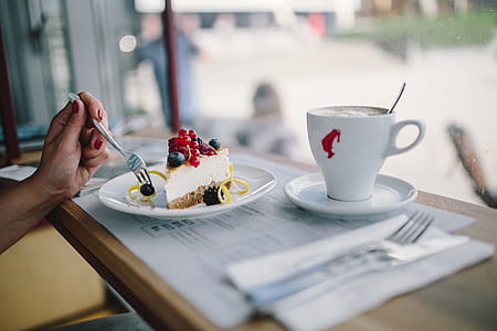 Woman Enjoying Cheese Cake and a Coffee with Fruits in a Cafeteria thumbnail