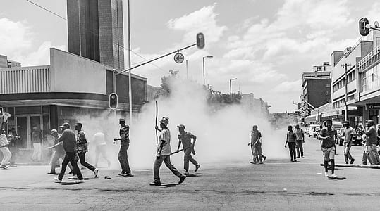 crowd of people running on concrete road near smoke screen thumbnail