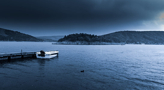 white boat on body of water under black sky thumbnail