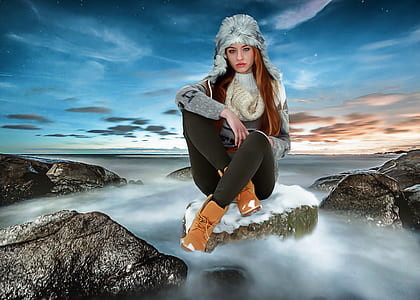 woman in gray sweater sitting on gray rock thumbnail
