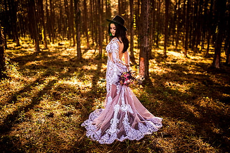 woman white brown and white long-sleeved dress standing in middle of trees during daytime thumbnail